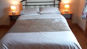 Un grand lit avec une tête de lit, deux tables de chevet avec des lampes et un plancher en bois.