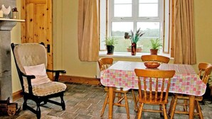 Un coin repas avec une table dressée pour quatre personnes, une chaise en bois et une fenêtre avec des rideaux.