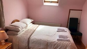 Ein Schlafzimmer mit Bett, Nachttisch, Lampe und Fenster.