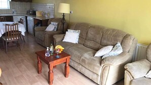 Ein Wohnzimmer mit einer Couch, einem Holztisch und einem Essbereich mit Tisch und Stühlen.