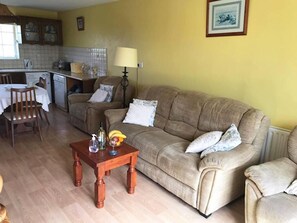 Ein Wohnzimmer mit einer Couch, einem Holztisch und einem Essbereich mit Tisch und Stühlen.