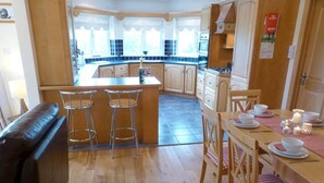 A kitchen with a central island, bar stools, a dining table with chairs, and a sofa.
