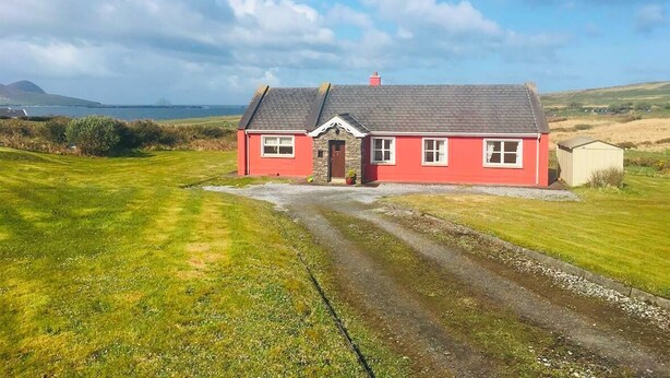 A red house with a stone foundation, a grey roof, and a gravel driveway. - 4 Bed in Dunquin (oc-ii08697) (Dunquin)