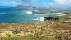A coastal landscape with rocky outcrops, grassy terrain, and a clear sky. - 4 Bed in Dunquin (oc-ii08697) (Dunquin)