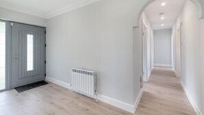Un couloir avec un radiateur, une porte grise et un plancher de couleur claire.