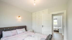 Une chambre à coucher comprenant un lit, une armoire, une table de chevet et un luminaire fixé au mur.