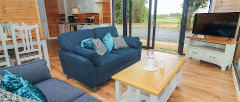 Ein gemütliches Blockhaus-Interieur mit einer Couch, einem Couchtisch und einem Fernsehbereich.