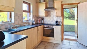 Una cocina con armarios de madera, encimera negra, horno de acero inoxidable y ventana con vistas al exterior.