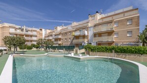 A residential building with a swimming pool, balconies, and a clear sky. - Apartment 'Las Conchas' with Sea View, Wi-Fi and Air Conditioning (Cunit)