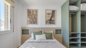 A bedroom with a bed, a wardrobe, and two framed pictures on the wall. - Apartment 'Las Conchas' with Sea View, Wi-Fi and Air Conditioning (Cunit)