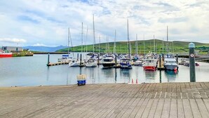 A marina with boats docked, a wooden dock, and a hilly landscape in the background. - 3 Bed in Dingle (oc-ii05995) (Dingle)