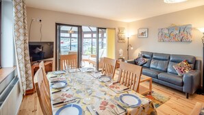 A dining area with a table set for four, a sofa, and a television. - 3 Bed in Dingle (oc-ii05995) (Dingle)