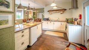 Una cocina con armarios de madera, una isla central, iluminación colgante y un perchero.