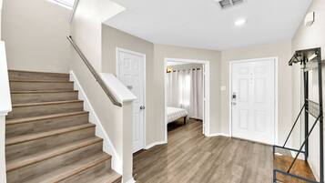 A staircase leading to a bedroom with a bed, a door, and a ceiling vent.