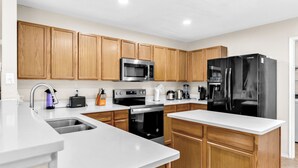 Una cocina moderna con armarios de madera, electrodomésticos de acero inoxidable y encimera blanca.