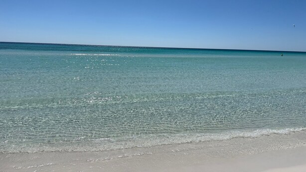 Ein Strand mit klarem Wasser und blauem Himmel.