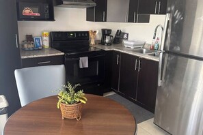 A compact kitchen with a microwave, stove, sink, and stainless steel refrigerator. - 1 Bedroom Apartment / Torre Lara (Tegucigalpa)