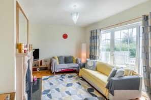 A living room with a sofa, a TV, a fireplace, and a large window with curtains. - 3 Bed in Moville (oc-ii07029) (Moville)