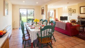 Un coin repas avec une table dressée pour quatre personnes, des chaises, un téléviseur et une cheminée.