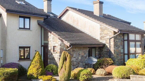 Une maison à deux étages avec des murs en pierre, un toit en pente et une antenne parabolique.