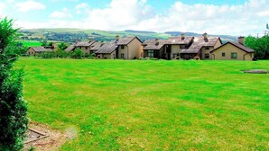 Une rangée de maisons, avec un champ verdoyant au premier plan et des collines en arrière-plan.