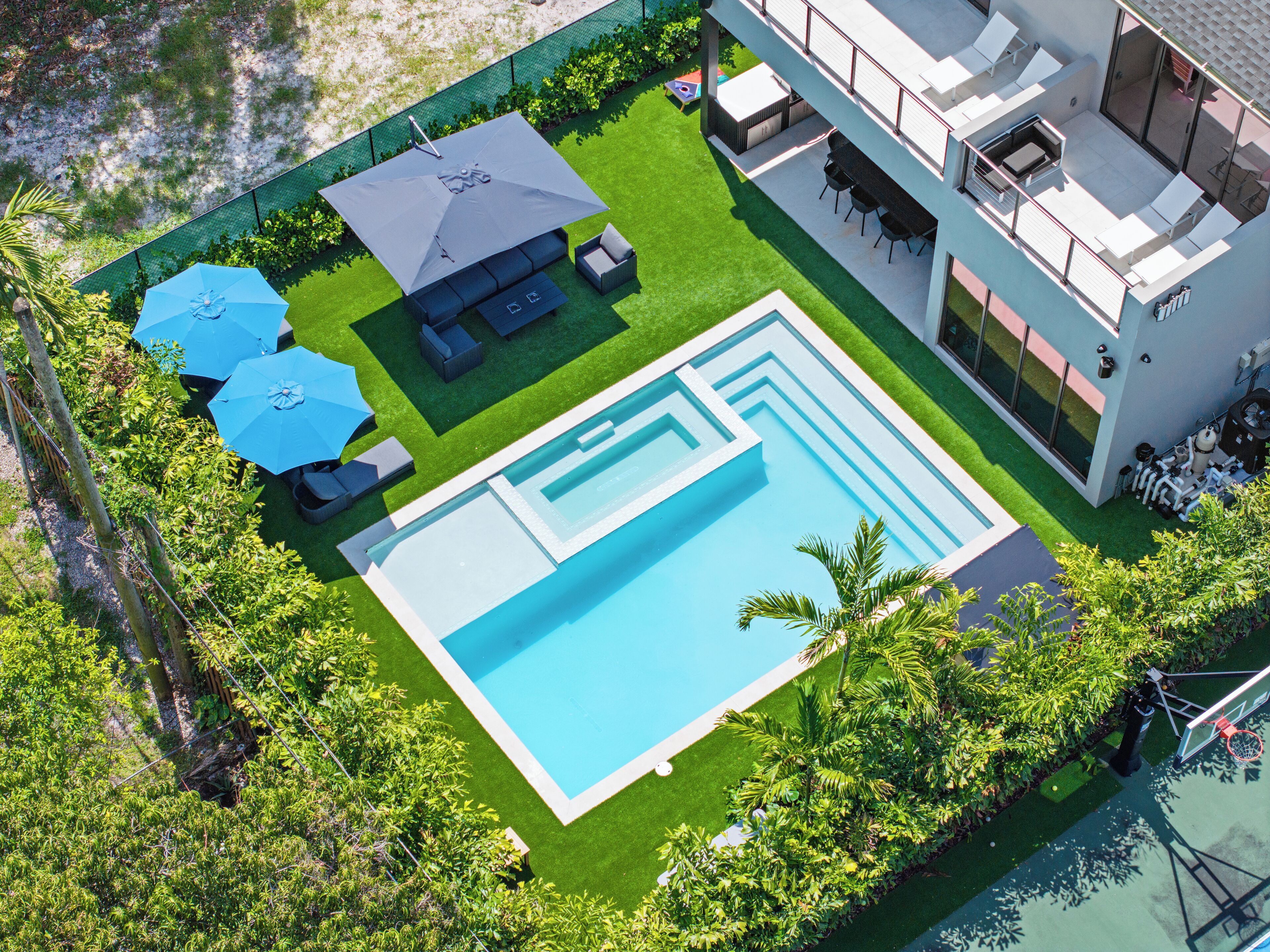 Une maison moderne dotée d’une piscine, d’un espace salon extérieur et d’un jardin clôturé.