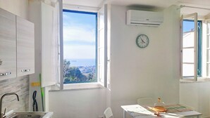 Une cuisine avec une fenêtre, un climatiseur, une horloge et une vue sur la mer.