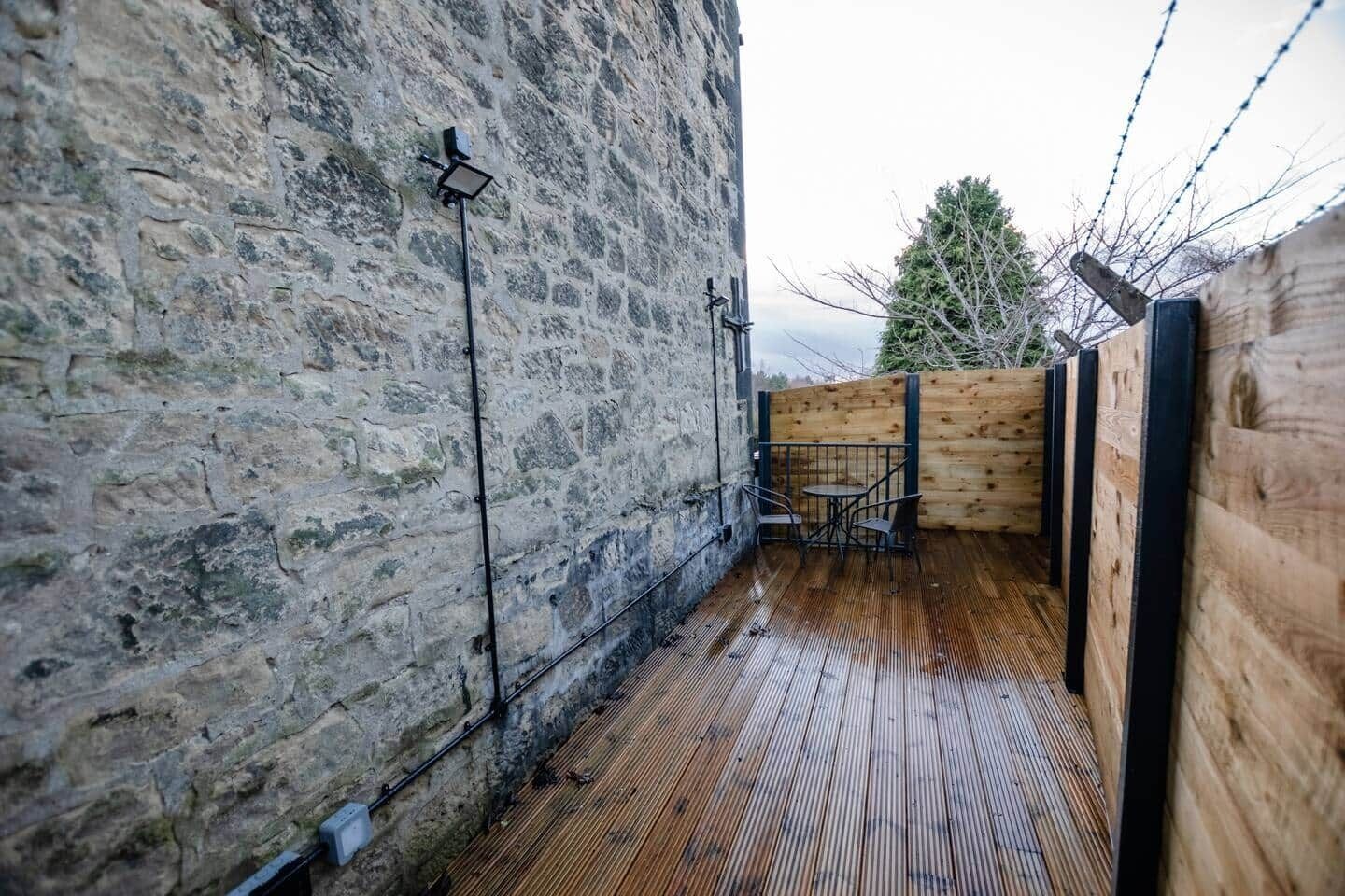 Un muro in pietra, un pontile di legno e una ringhiera metallica.