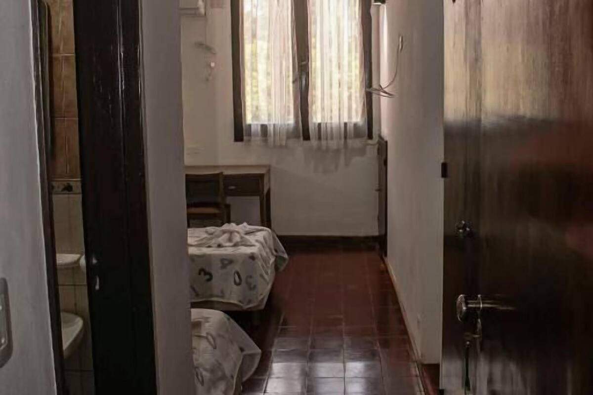 Un couloir étroit avec un lit, un bureau et une porte.