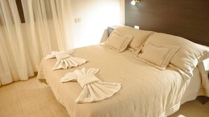A hotel room with a bed, curtains, and a wall-mounted light fixture.