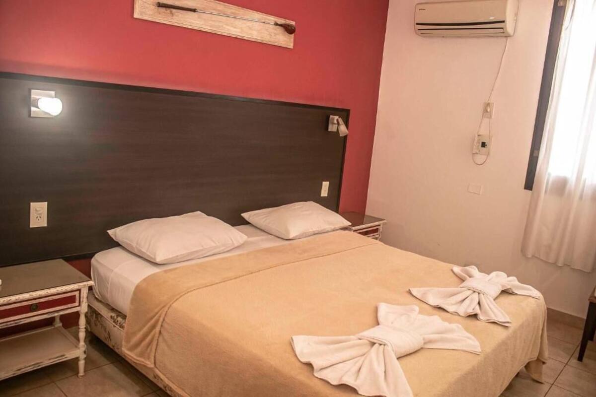 Un lit simple avec une couvre-lit beige, deux oreillers blancs et une serviette sur le lit.