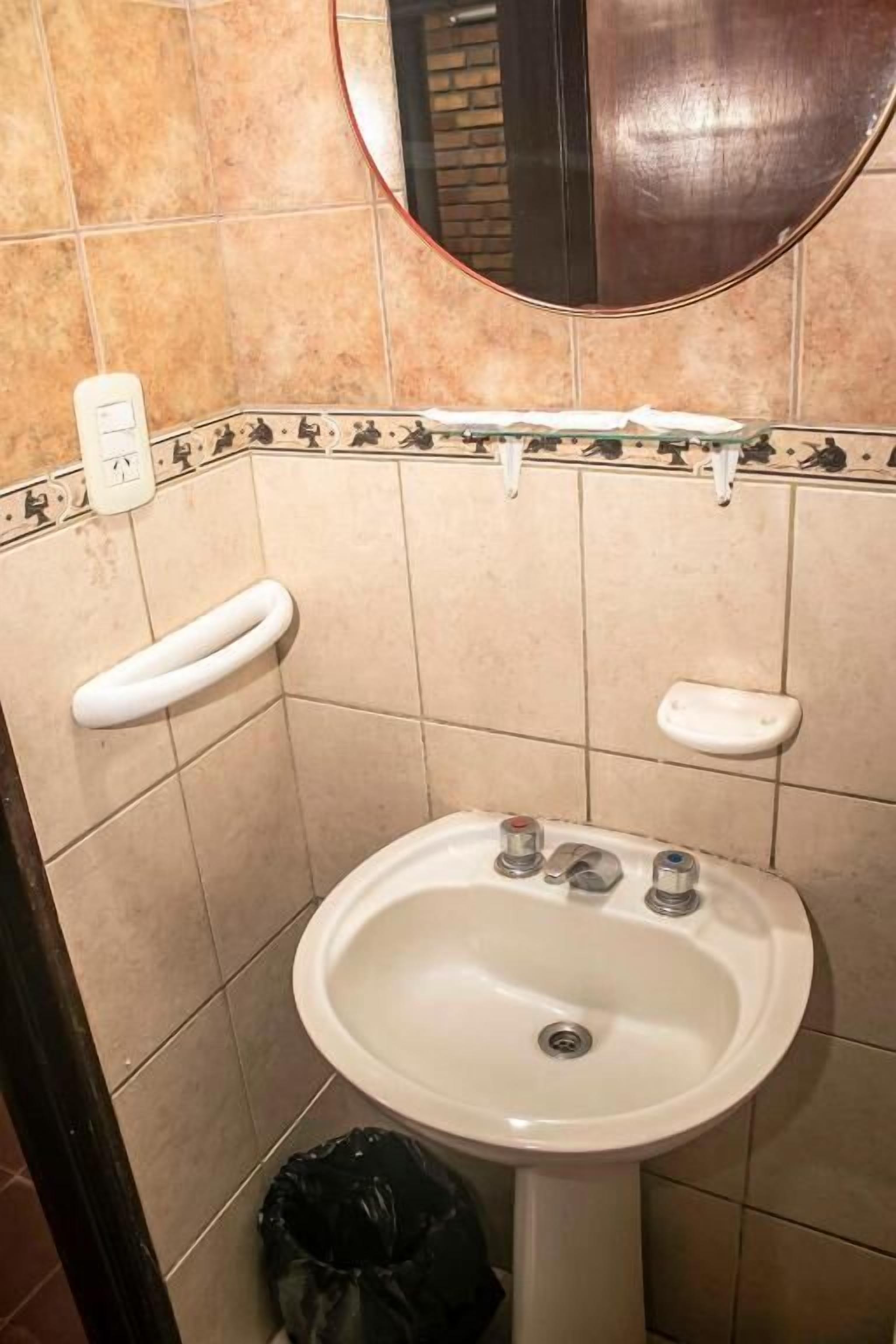 A bathroom with a white sink, a mirror, a towel rack, and a soap dish.