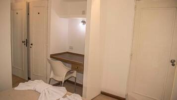 Una habitación con cama, escritorio, silla y dos puertas.
