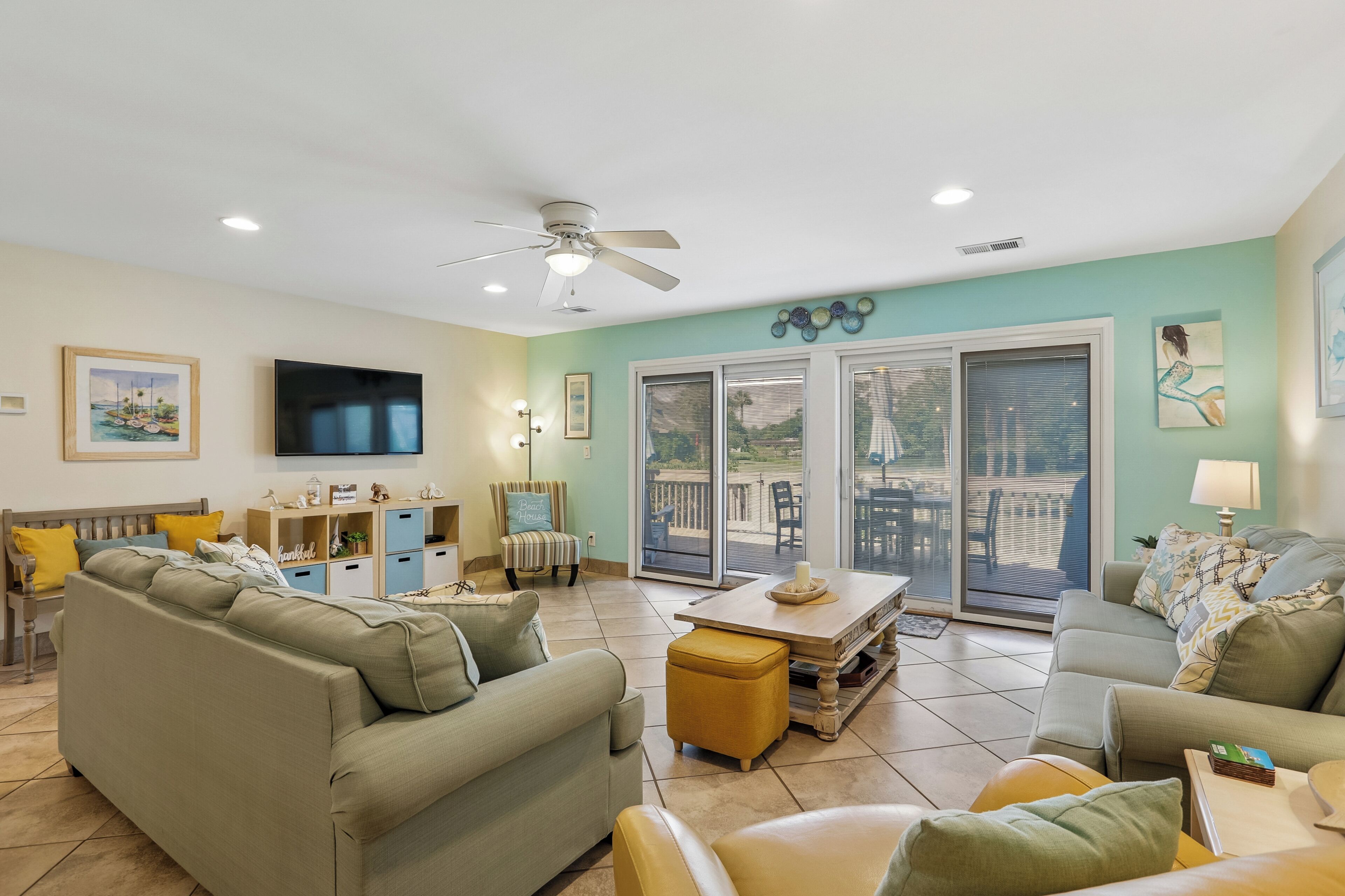 A living room with a television, sofas, a coffee table, and a ceiling fan.