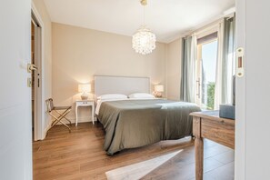 A bedroom with a bed, bedside tables, a chair, a desk, and a chandelier. - Tenuta Le Scuderie del Palio - Agritourism in Tuscany among the horses (Siena)