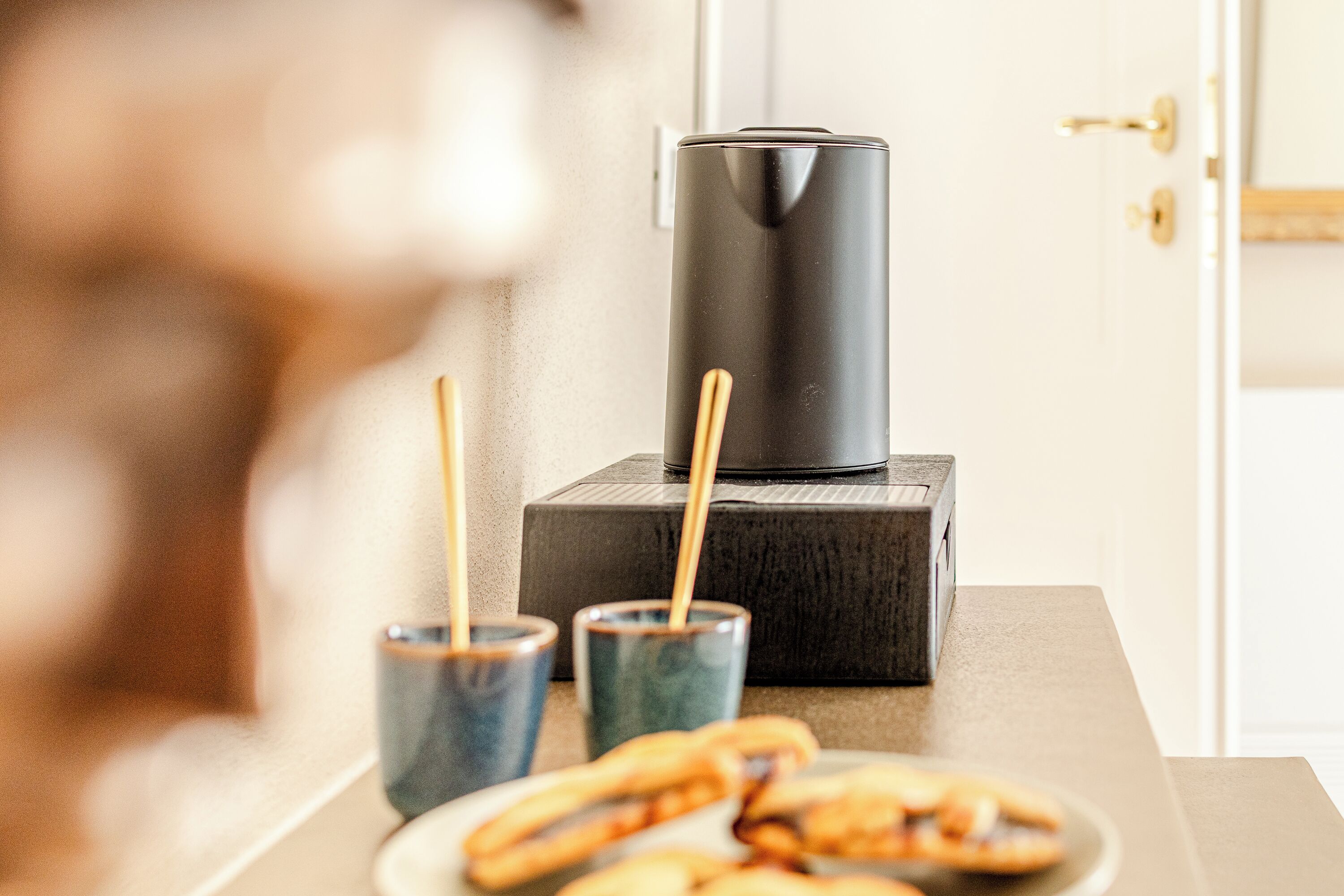 Un comptoir de cuisine avec une machine à café, deux verres et une assiette de bretzels.