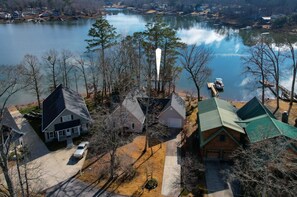 A residential area with houses near a lake, featuring a prominent white tower, a driveway, and a green-roofed house. - Lakefront Retreat | Dock + Sunset Views (Prosperity)