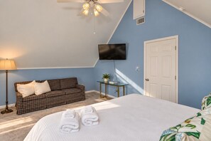 A bedroom with a bed, a sofa, a television, and a door. - Lakefront Retreat | Dock + Sunset Views (Prosperity)