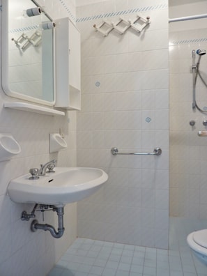 Ein Badezimmer mit Waschbecken, Spiegel, Handtuchhalter, Dusche und Toilette.