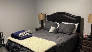 Un dormitorio con una cama, dos mesitas de noche, un ventilador de techo y una mesilla.