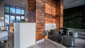 Un espace d’accueil moderne avec un mur d’accent en bois, un banc en marbre et une vue sur la verdure à l’extérieur.