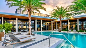 A pool area with lounge chairs, palm trees, and a building with large windows. - Luxury 1BR King Suite • Rooftop Pool • Hot Tub • Near Las Olas, Fort Lauderdale (Fort Lauderdale)