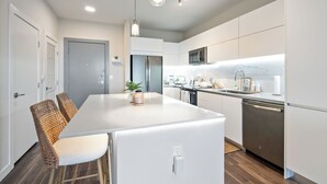 Une cuisine moderne avec des meubles blancs, un îlot central et des appareils électroménagers en acier inoxydable.