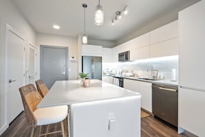 A modern kitchen with white cabinetry, a central island, and stainless steel appliances. - Luxury 1BR King Suite • Rooftop Pool • Hot Tub • Near Las Olas, Fort Lauderdale (Fort Lauderdale)