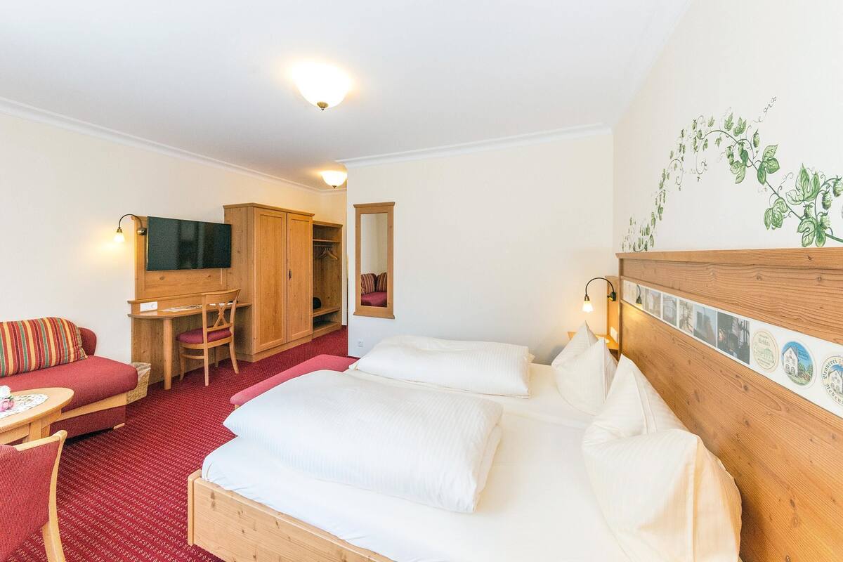 A hotel room with a bed, a sofa, a desk, and a wardrobe.