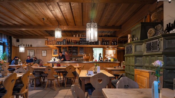 Un restaurant avec des meubles en bois, des luminaires suspendus et un coin bar.