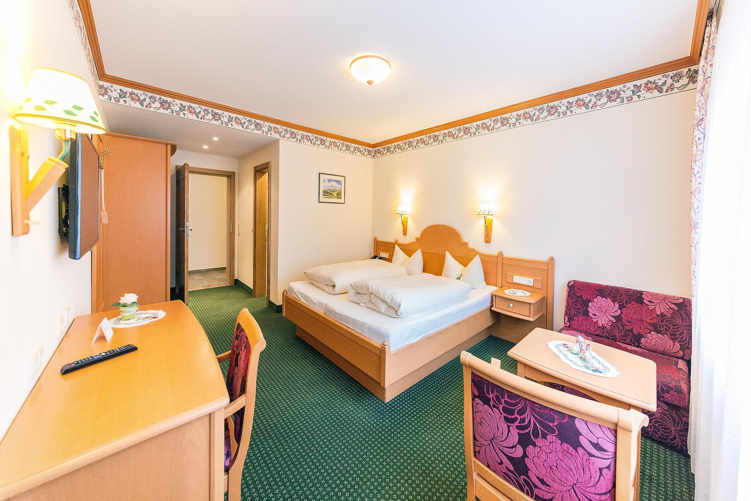 A hotel room with a bed, a desk, a chair, a small table, and a sofa.