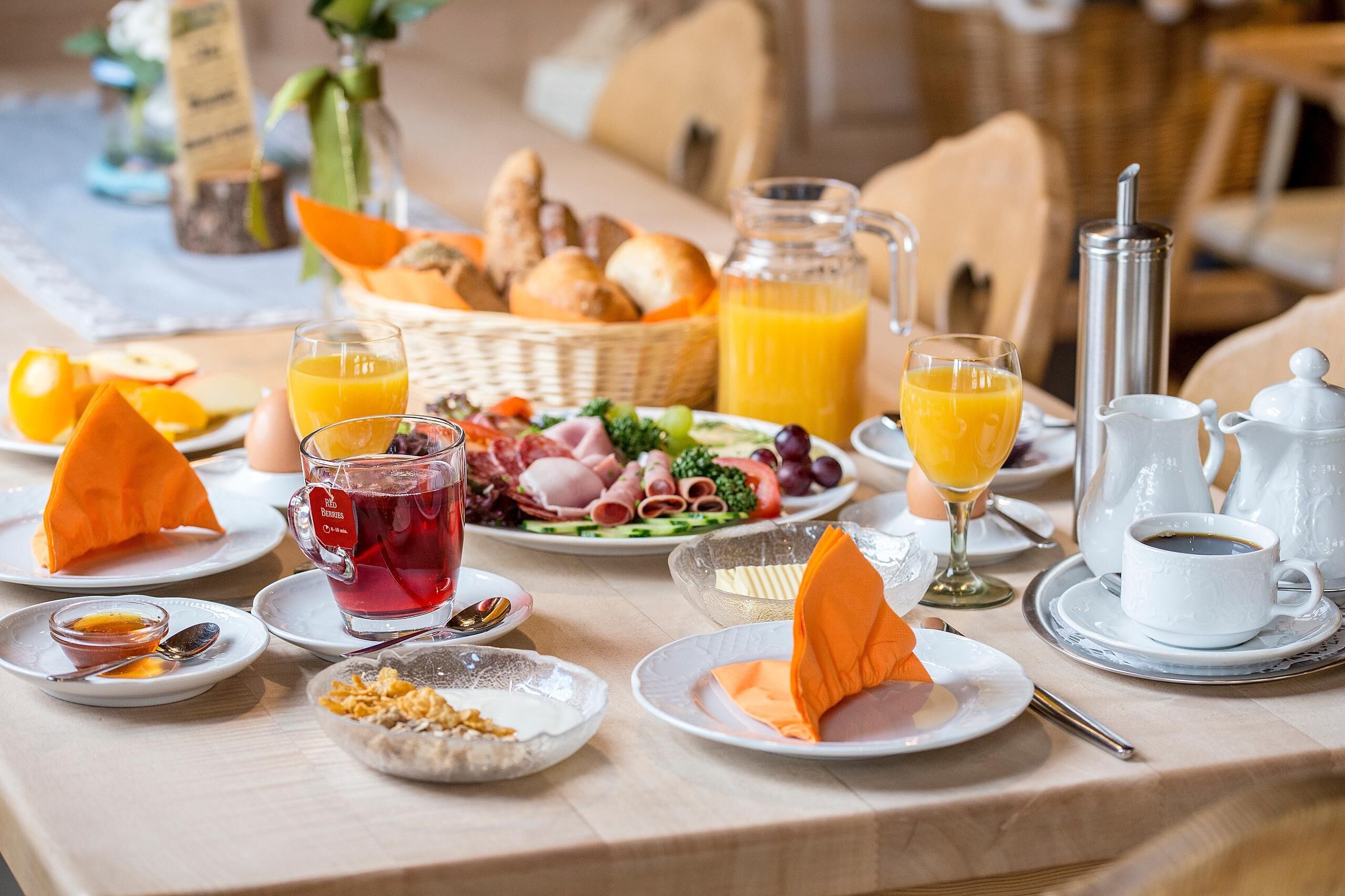 A breakfast setting with various food items, drinks, and dining utensils.