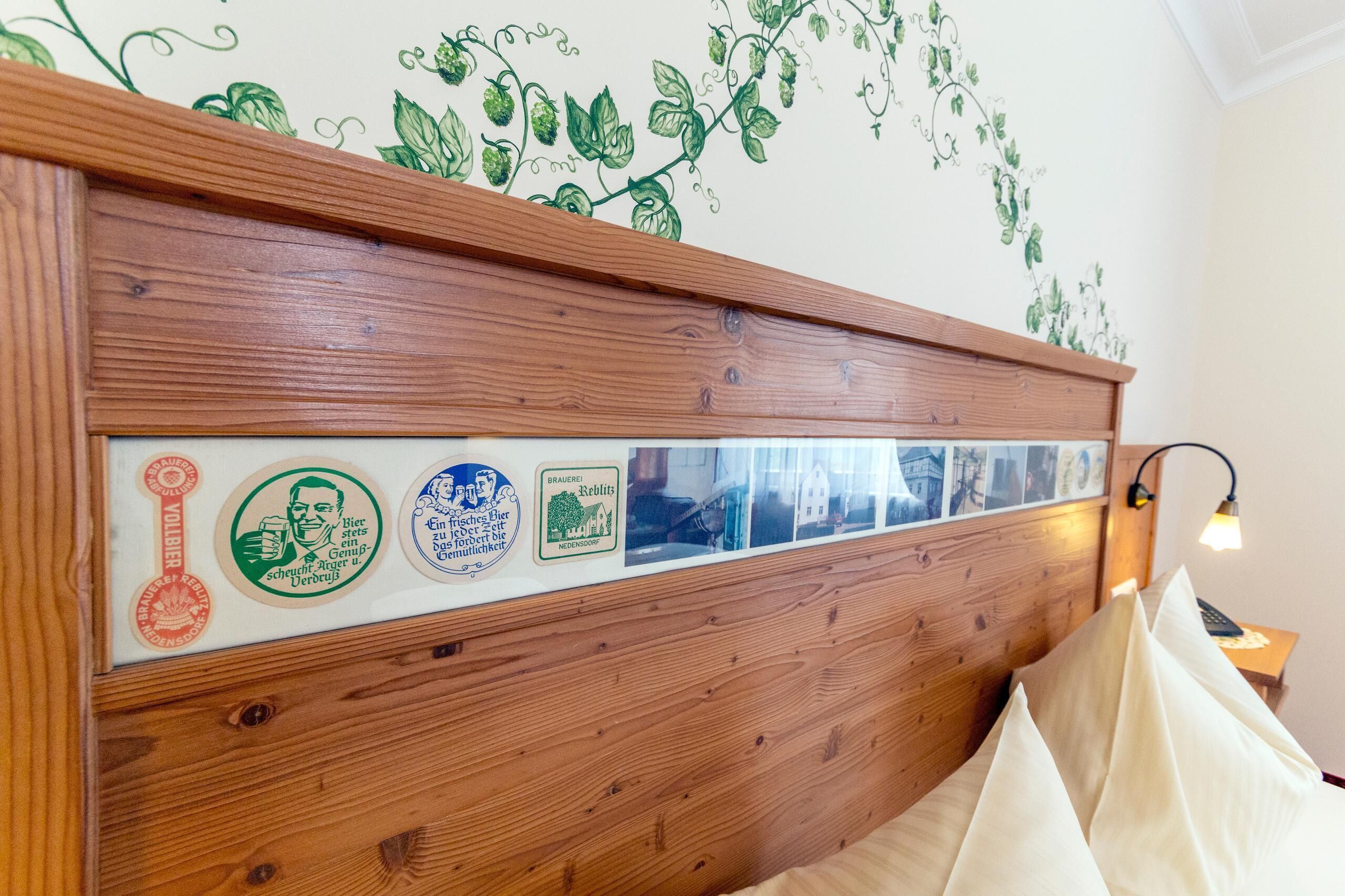 Un cabecero de madera decorado con una serie de insignias antiguas y un adhesivo mural con forma de hiedra verde.