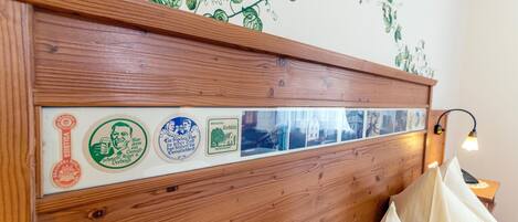 Un cabecero de madera decorado con una serie de insignias antiguas y un adhesivo mural con forma de hiedra verde.